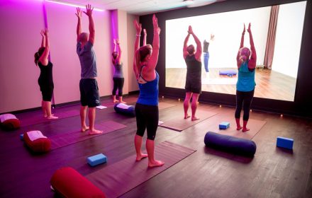 virtual fitness class on a screen in the facility with no instructors